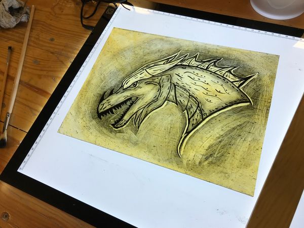 Student painted glass dragon design on lightbox